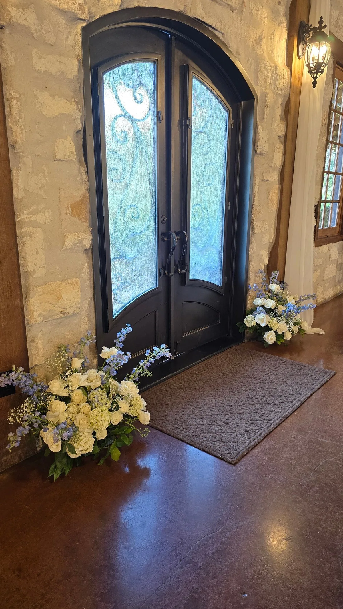 White and pale-blue flower arrangements beside a dark arched double doorway