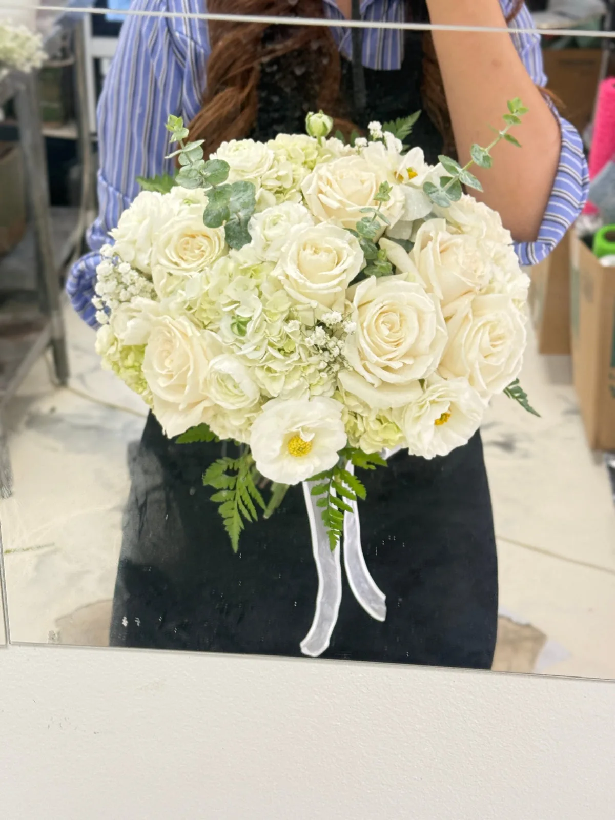 Round ivory and white bridal bouquet with greenery and trailing white ribbons