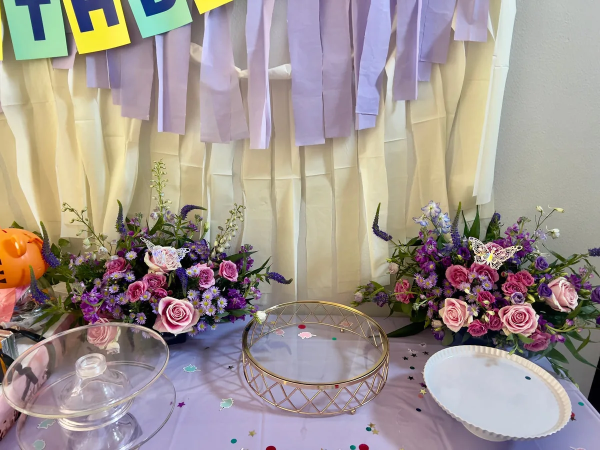 Pink, lavender and purple flower arrangements with butterfly accents on a lavender-covered celebration table