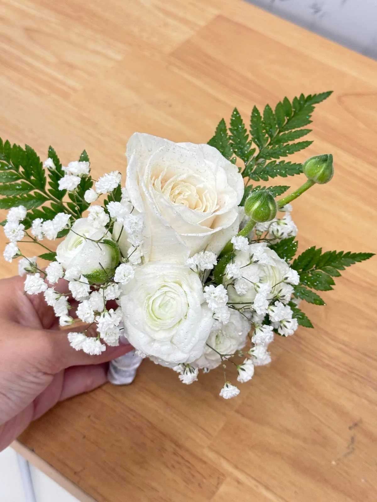Small white floral bundle with a rose, delicate white flowers and fern greenery